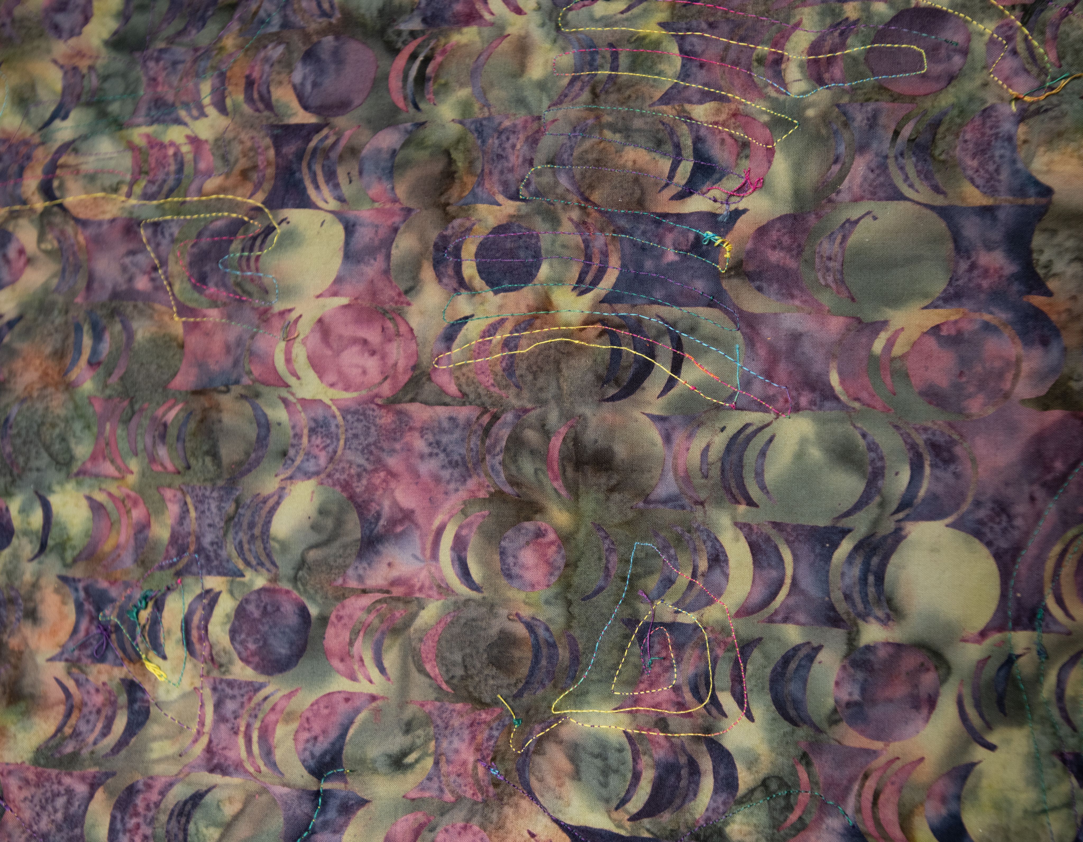 Banner image of a locally made quilt, made from multiple stitched pieces forming one unified design, representing a common endeavor.